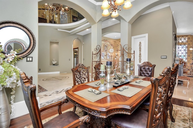 dining room featuring a towering ceiling, a chandelier, and wood finished floors