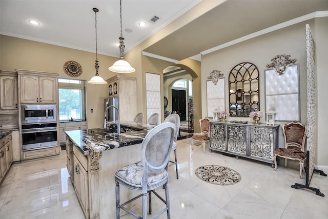 kitchen with arched walkways, a breakfast bar area, visible vents, appliances with stainless steel finishes, and dark stone counters