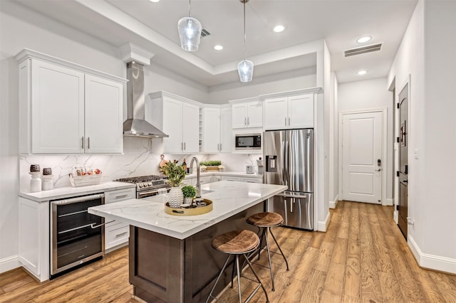 kitchen featuring beverage cooler, visible vents, wall chimney exhaust hood, appliances with stainless steel finishes, and backsplash