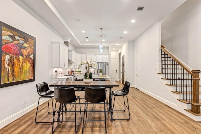 kitchen with light wood-style floors, white cabinetry, a kitchen island, and visible vents