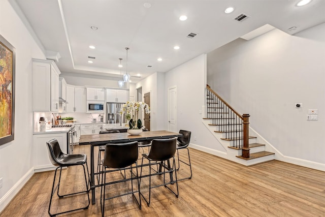 kitchen featuring a kitchen island with sink, stainless steel appliances, light wood-style flooring, and visible vents