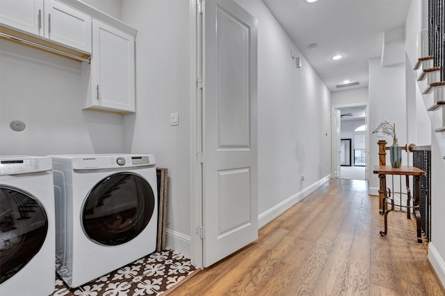 laundry room with cabinet space, light wood-style flooring, baseboards, and separate washer and dryer