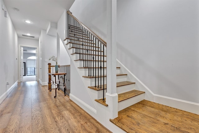 staircase featuring visible vents, baseboards, wood finished floors, and recessed lighting