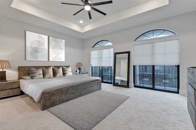 carpeted bedroom with baseboards, ceiling fan, access to exterior, a tray ceiling, and recessed lighting