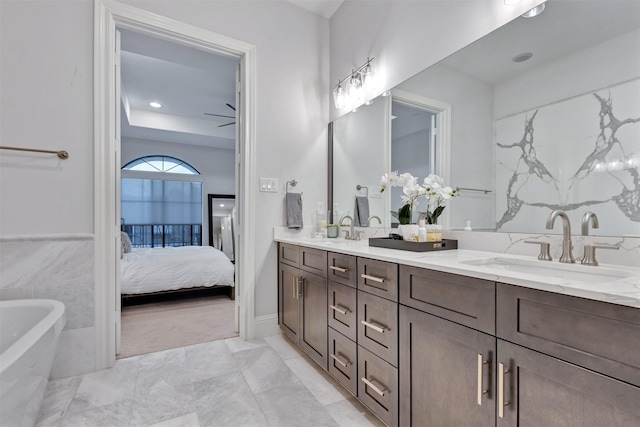 bathroom featuring ensuite bathroom, double vanity, a freestanding bath, and a sink