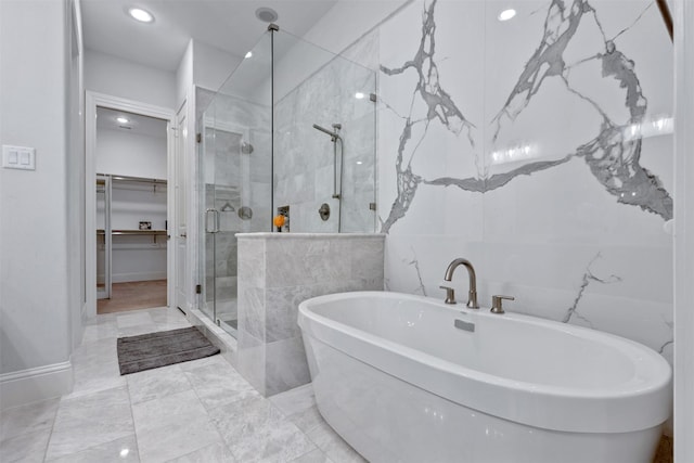 bathroom featuring a shower stall, tile walls, a walk in closet, and a freestanding bath