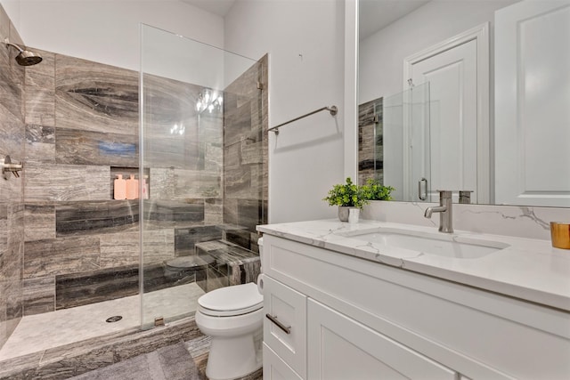 bathroom with a stall shower, vanity, and toilet