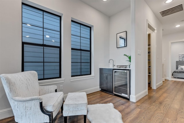 sitting room featuring recessed lighting, beverage cooler, dark wood-type flooring, visible vents, and wet bar