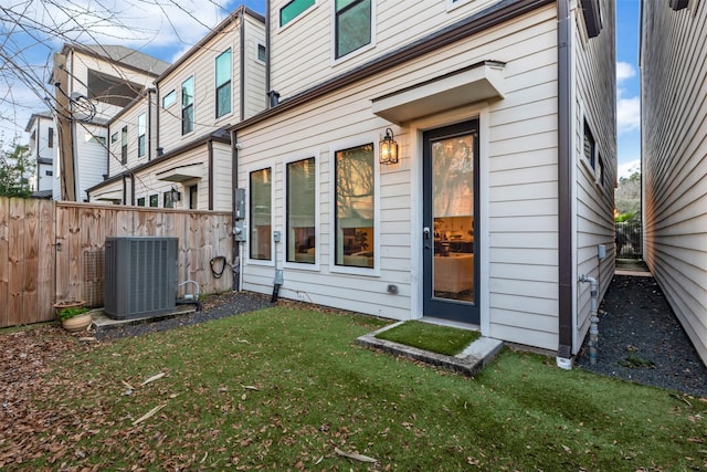 rear view of house featuring a yard, central AC, and fence