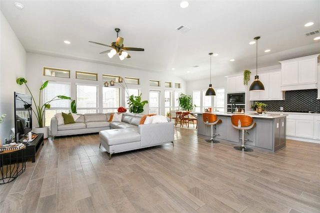 living area with light wood-style flooring, visible vents, and recessed lighting