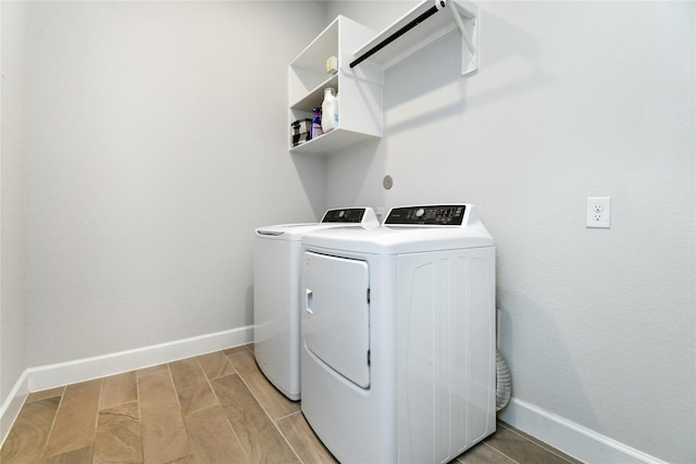 clothes washing area featuring washer and dryer, laundry area, wood finish floors, and baseboards