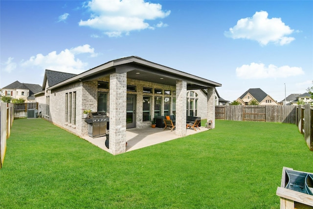 rear view of house featuring a lawn, a fenced backyard, cooling unit, a patio area, and brick siding