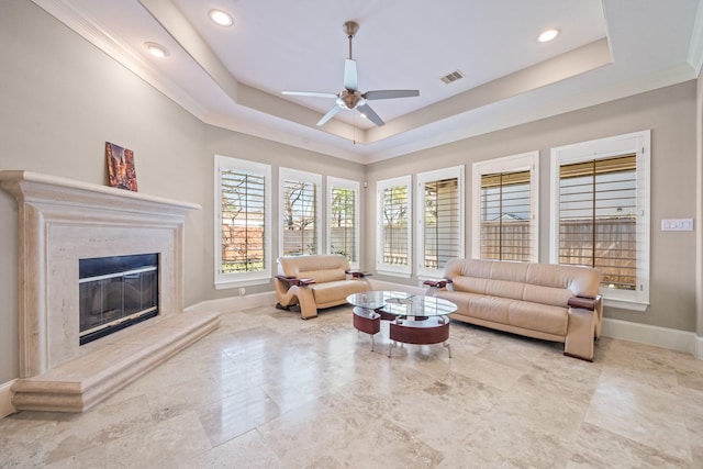 living area with a tray ceiling, a fireplace, visible vents, and baseboards