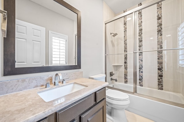 bathroom featuring toilet, combined bath / shower with glass door, and vanity