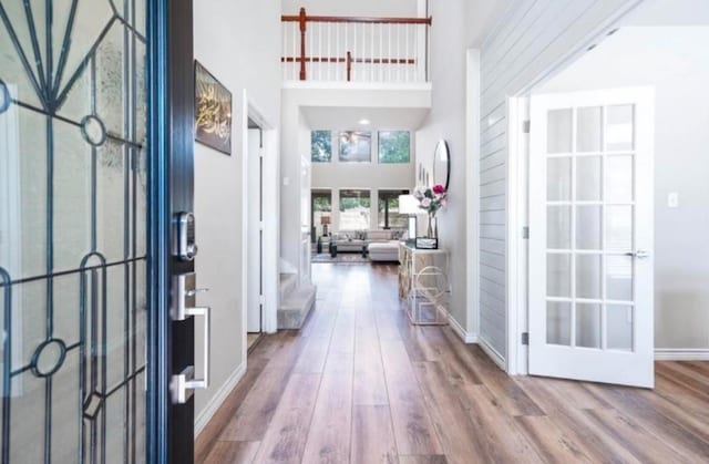 entryway with a towering ceiling, baseboards, and wood finished floors