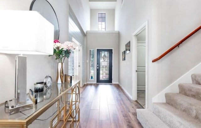 foyer with baseboards, stairway, a towering ceiling, and wood finished floors