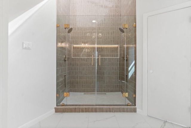 full bath with baseboards, marble finish floor, and a stall shower