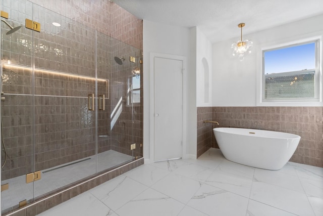 full bathroom featuring a shower stall, wainscoting, a freestanding tub, marble finish floor, and tile walls