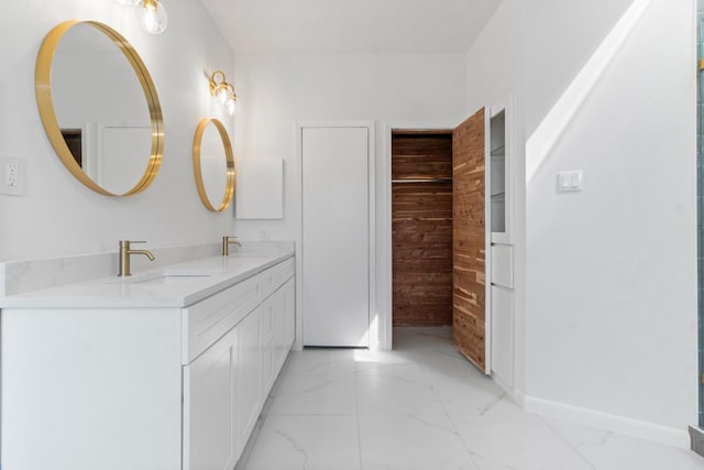 bathroom with double vanity, marble finish floor, baseboards, and a sink