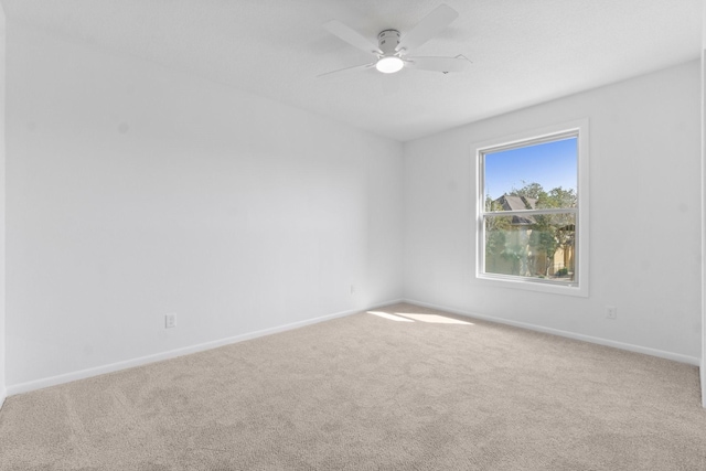 carpeted empty room featuring baseboards and ceiling fan