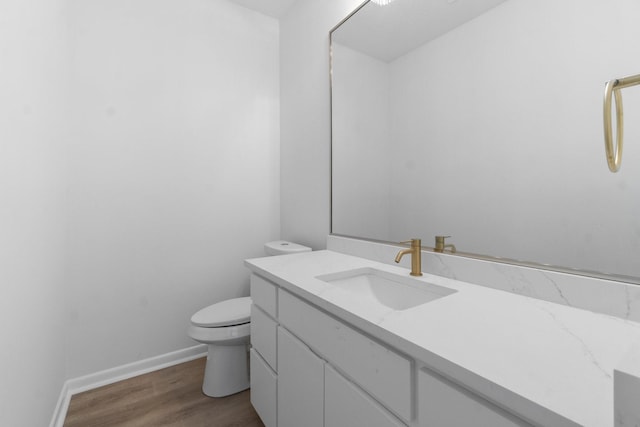 bathroom with baseboards, toilet, wood finished floors, and vanity