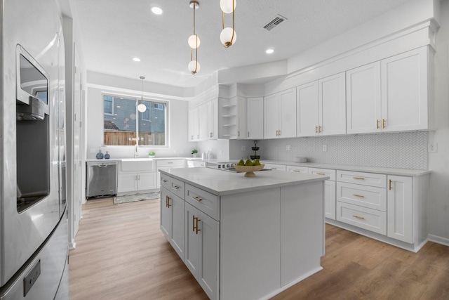 kitchen with open shelves, light wood-style floors, stainless steel dishwasher, and white cabinets