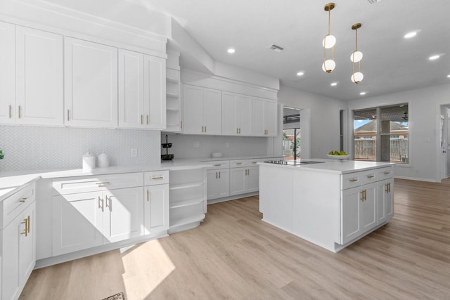 kitchen with a kitchen island, open shelves, light wood-style flooring, white cabinets, and tasteful backsplash