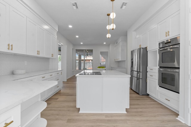 kitchen with stainless steel appliances, a kitchen island, visible vents, and white cabinetry