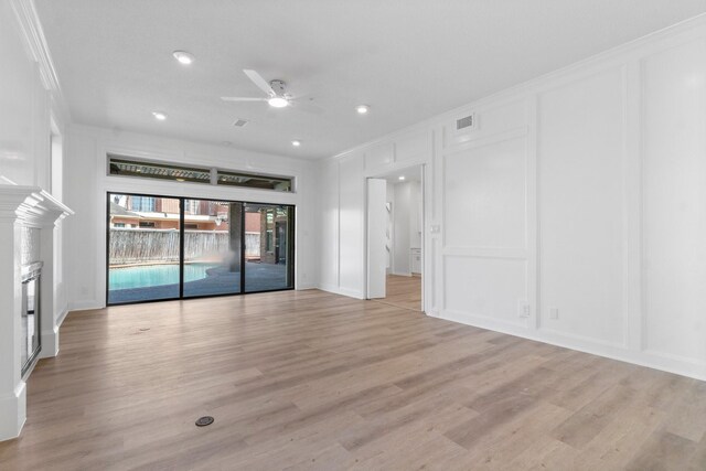 empty room featuring light wood-style flooring, ornamental molding, a ceiling fan, and a decorative wall