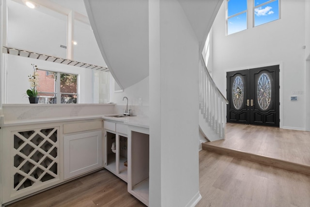 bar featuring a sink, stairway, light wood-type flooring, and a healthy amount of sunlight