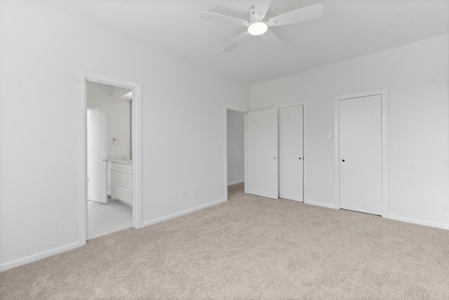 unfurnished bedroom featuring baseboards, multiple closets, carpet floors, and connected bathroom