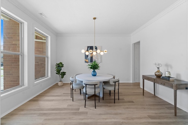 dining room with light wood-type flooring, visible vents, a chandelier, and ornamental molding