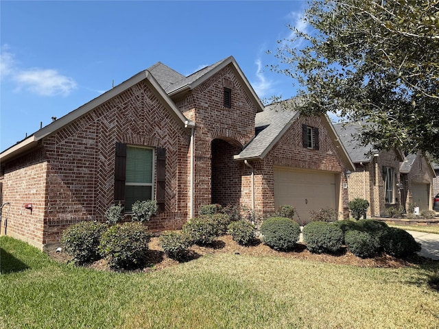 view of front of house featuring an attached garage, roof with shingles, a front yard, and brick siding