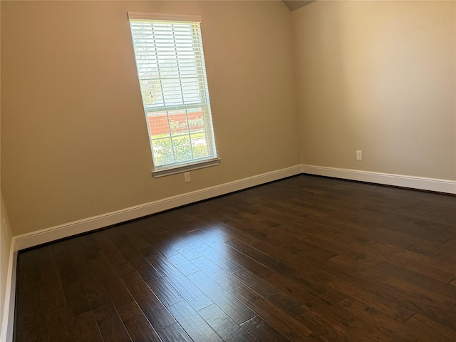 spare room with dark wood-type flooring and baseboards