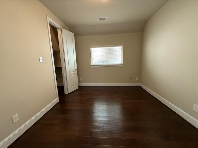 unfurnished room featuring dark wood-style floors, visible vents, and baseboards