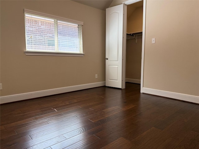 unfurnished bedroom featuring a closet, dark wood finished floors, and baseboards