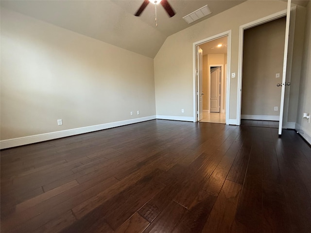 interior space featuring dark wood-type flooring, a ceiling fan, visible vents, vaulted ceiling, and baseboards