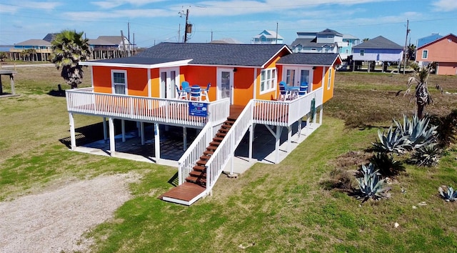 back of property with roof with shingles, a yard, driveway, and a wooden deck