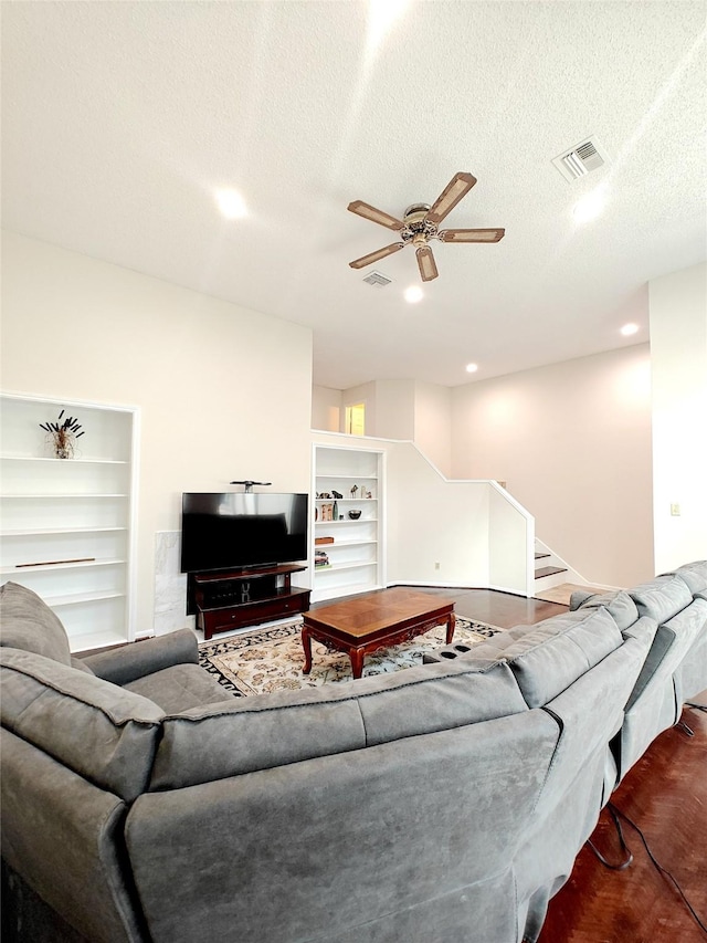 living room with a textured ceiling, built in shelves, and visible vents