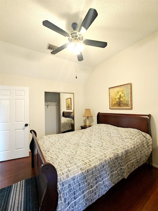 bedroom featuring visible vents, dark wood finished floors, vaulted ceiling, a textured ceiling, and a closet