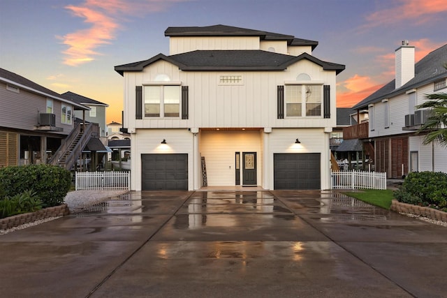 view of front facade featuring a garage, driveway, board and batten siding, and fence