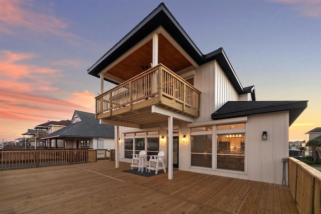 rear view of property featuring a balcony, board and batten siding, and a wooden deck