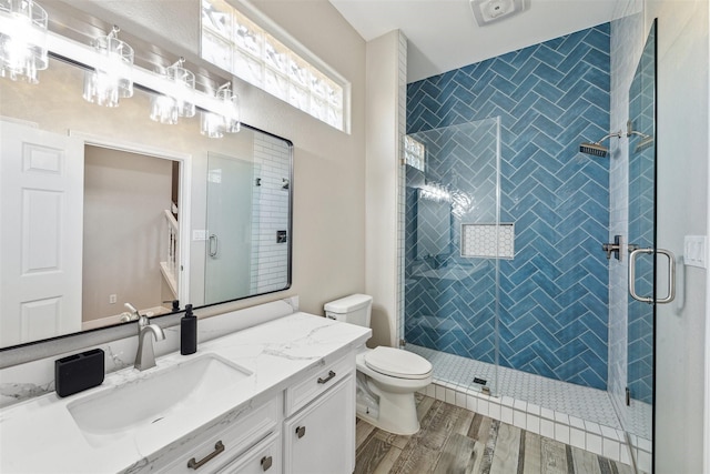 full bath featuring vanity, a stall shower, wood finished floors, and toilet