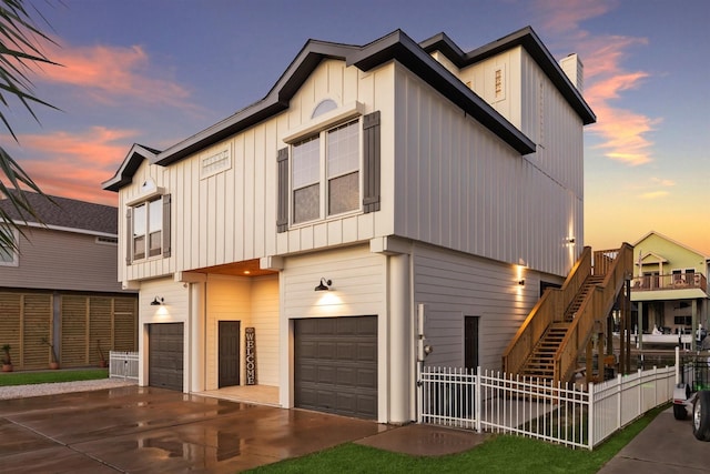 view of front facade with an attached garage, fence, concrete driveway, stairway, and board and batten siding