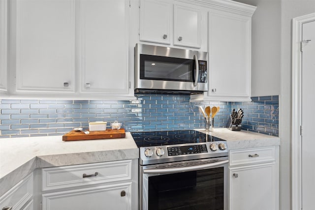 kitchen with appliances with stainless steel finishes, light countertops, white cabinets, and tasteful backsplash