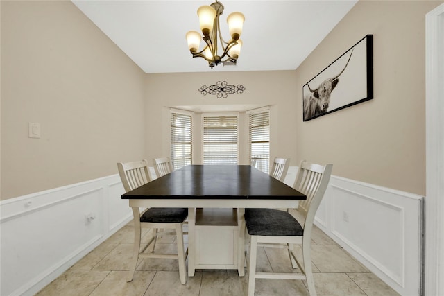 dining space with light tile patterned floors, a chandelier, and wainscoting