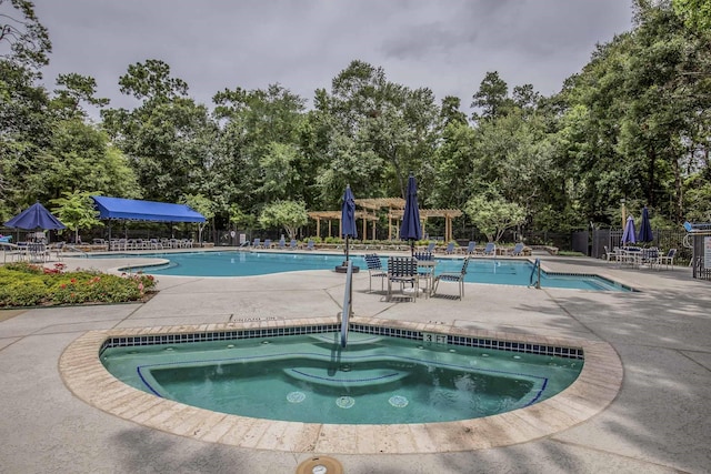 pool with a patio area, fence, and a hot tub