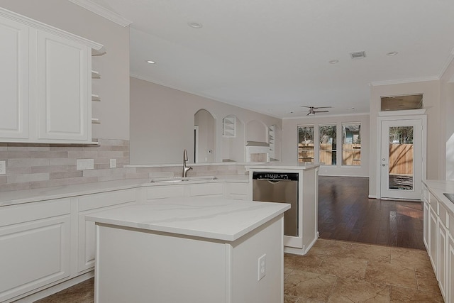 kitchen featuring a peninsula, a sink, white cabinetry, ornamental molding, and decorative backsplash