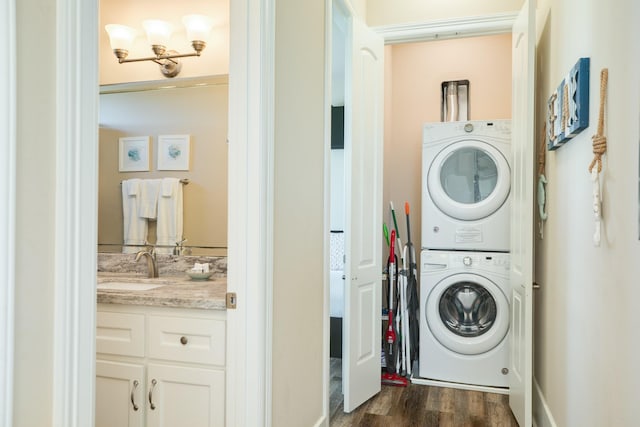 clothes washing area with laundry area, dark wood-style flooring, a sink, and stacked washer / drying machine