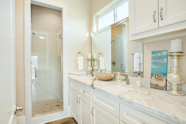 full bath with double vanity, a stall shower, and a sink